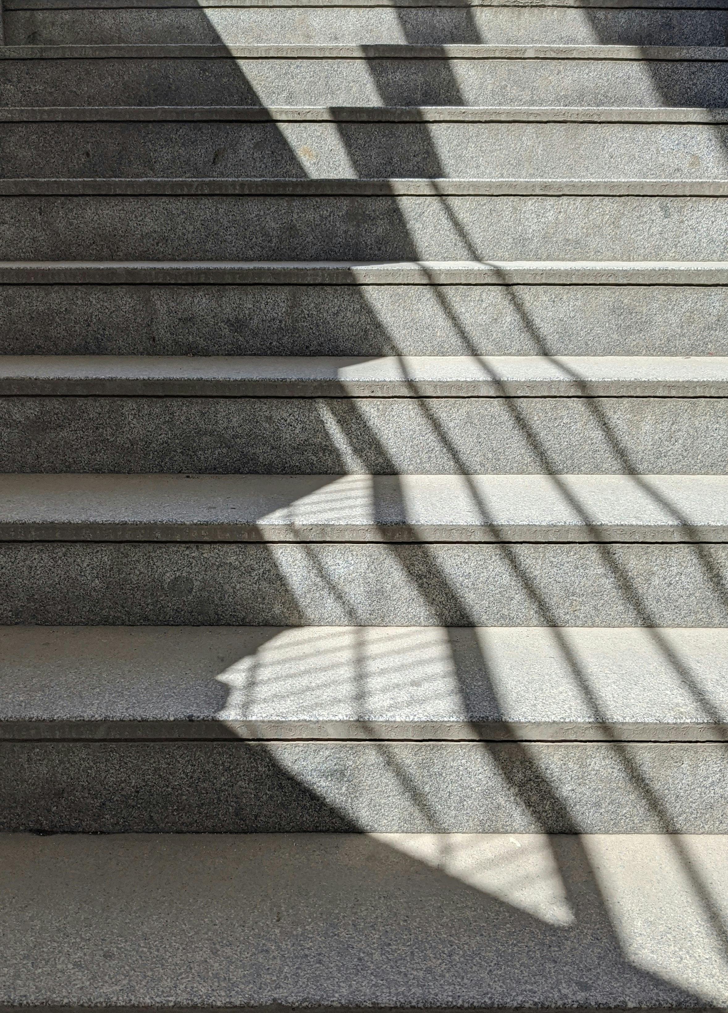A geometric play of shadows on an outdoor concrete staircase under sunlight.