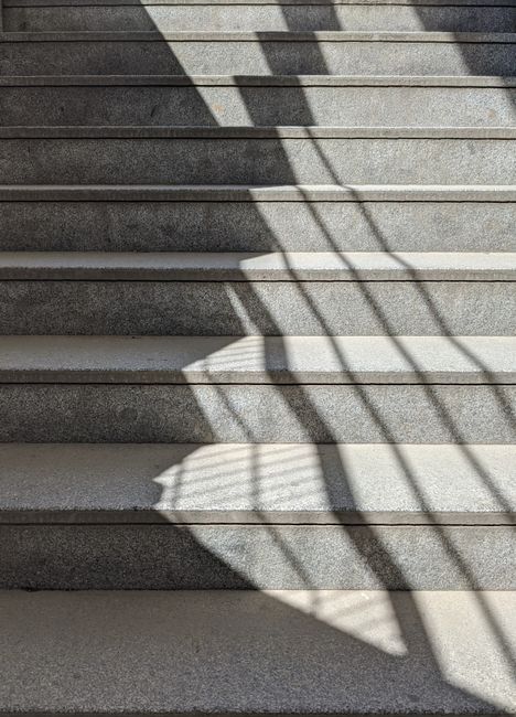 A geometric play of shadows on an outdoor concrete staircase under sunlight.