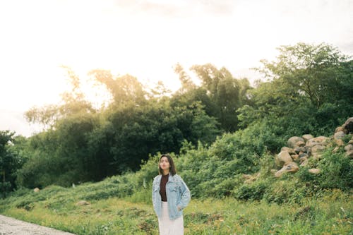 A woman standing on a road in the middle of a field