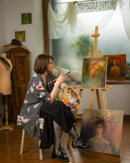 Free Woman in art studio painting on canvases, surrounded by artistic decor. Stock Photo