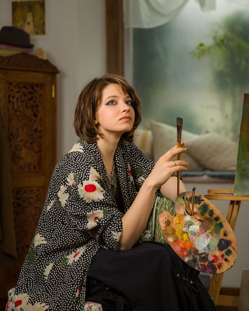 Free Elegant young woman artist holding a paintbrush in a creative studio setting. Stock Photo