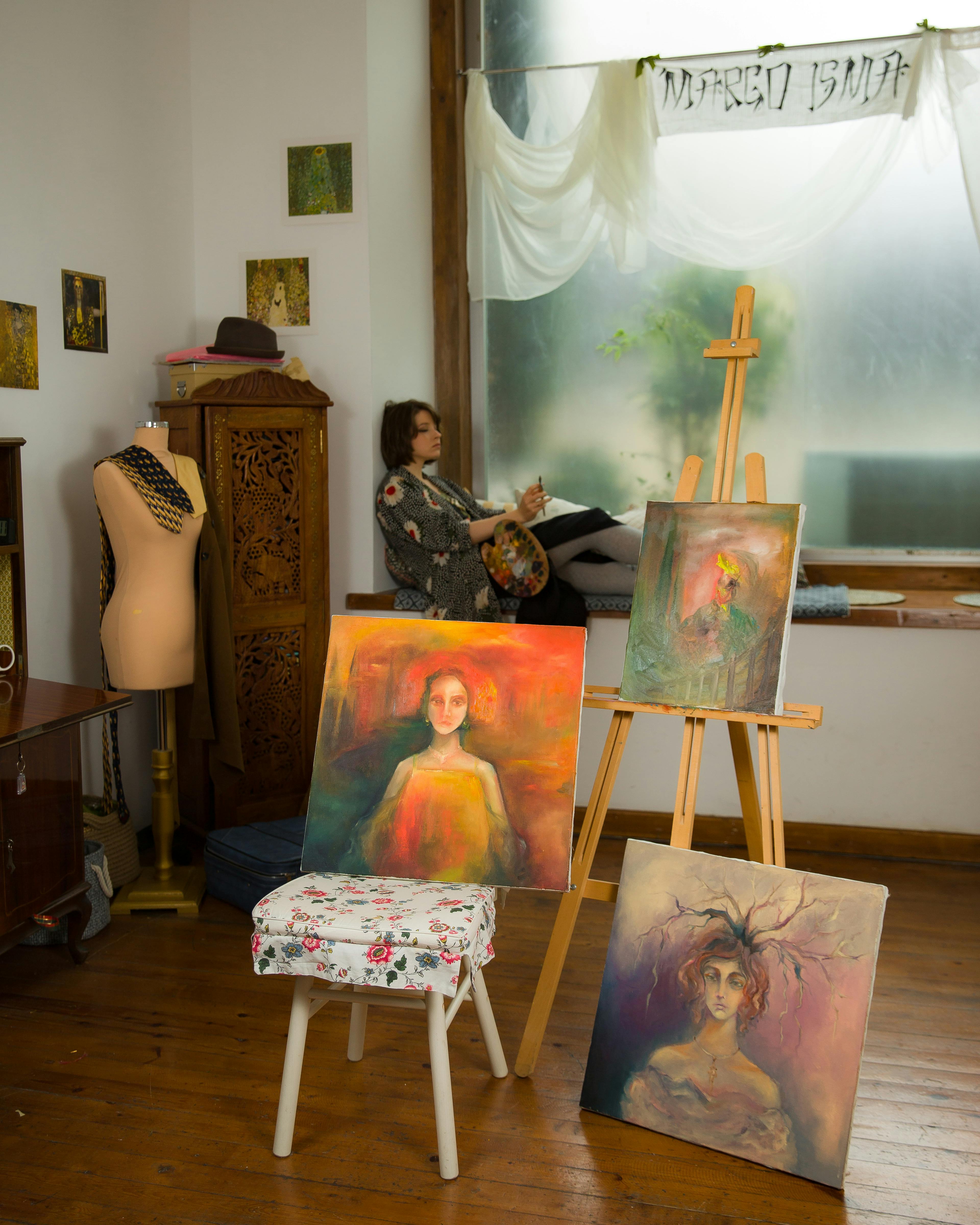 Cozy art studio showcasing vibrant paintings and a focused artist creating new work.