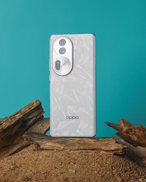 A white phone with a camera on it sitting on a log