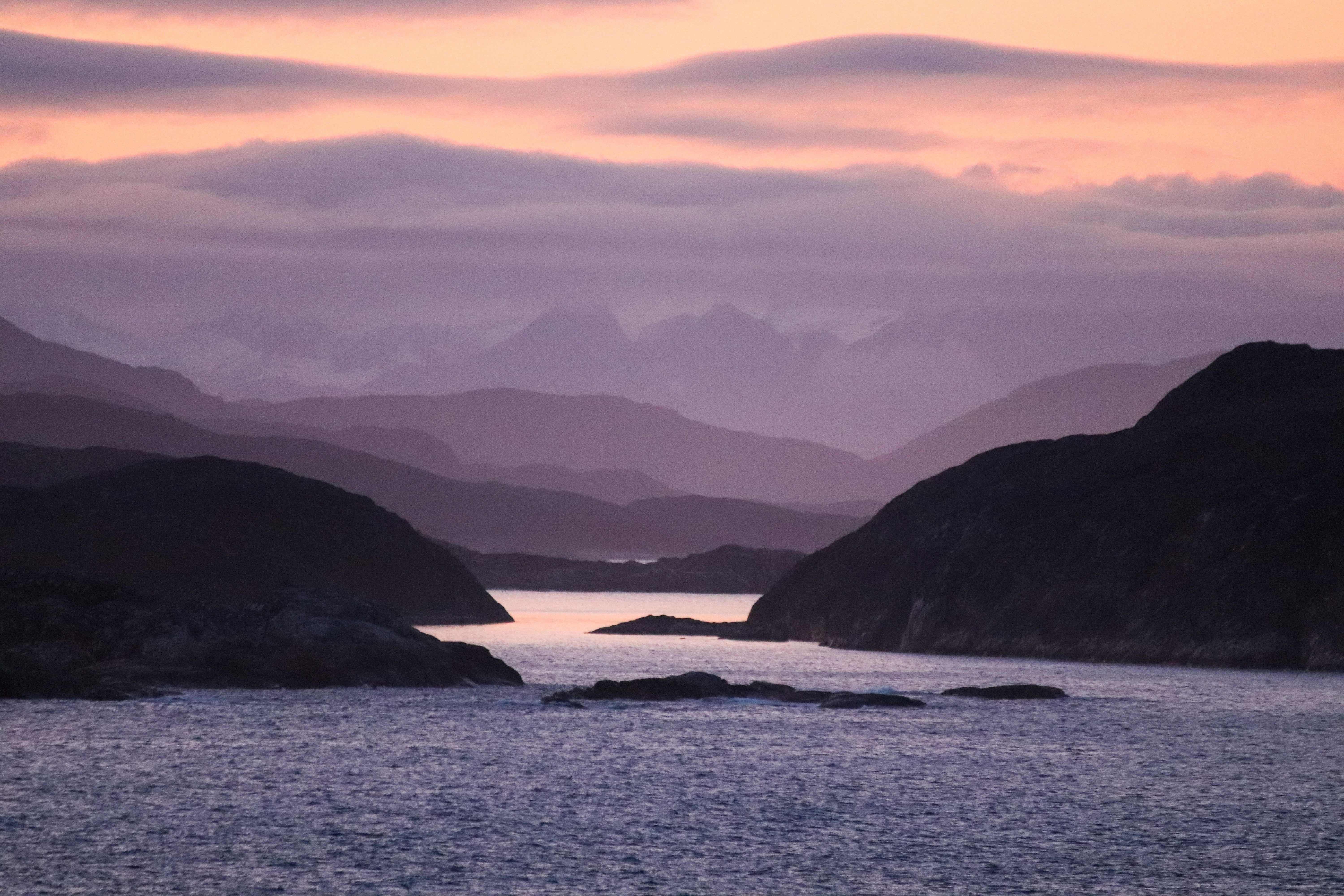 A tranquil scene capturing a misty bay at twilight, with layers of mountains and a serene ambiance.