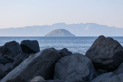 Scenic View of Rocky Shoreline with Distant Mountains across the Water