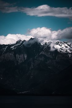 Stunning aerial view of snowcapped mountains and clouds against a deep contrasting sky.