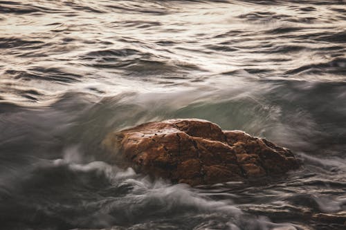 A rock in the ocean with waves crashing on it