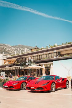 Two luxury red sports cars parked in Monte Carlo, Monaco, under a clear sky.