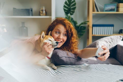 Free A woman laying on the bed with her dog Stock Photo