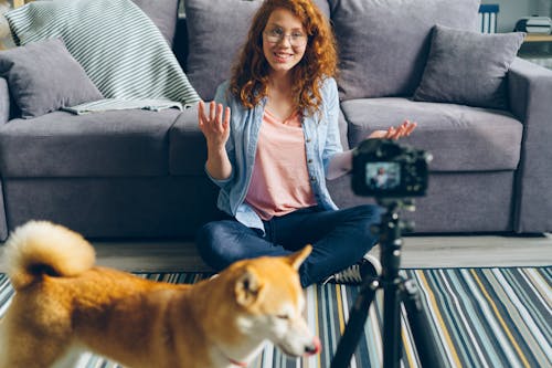 A woman sitting on the floor with a dog and a camera