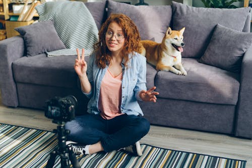 A woman sitting on the floor with a dog and a camera