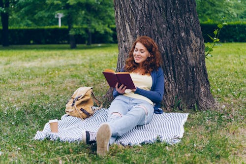 A woman sitting on the grass reading a book