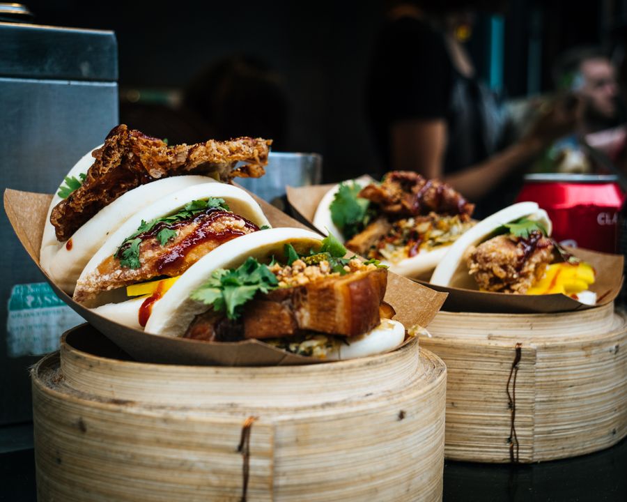 Ångade bao-bröd fyllda med krispig kyckling och färsk koriander i bambukorgar.