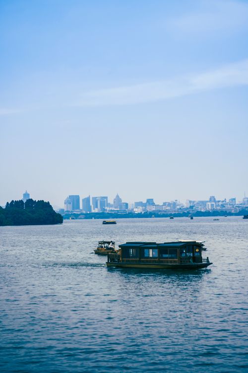 Free Picturesque view of boats on West Lake with Hangzhou skyline, ideal for travel enthusiasts. Stock Photo