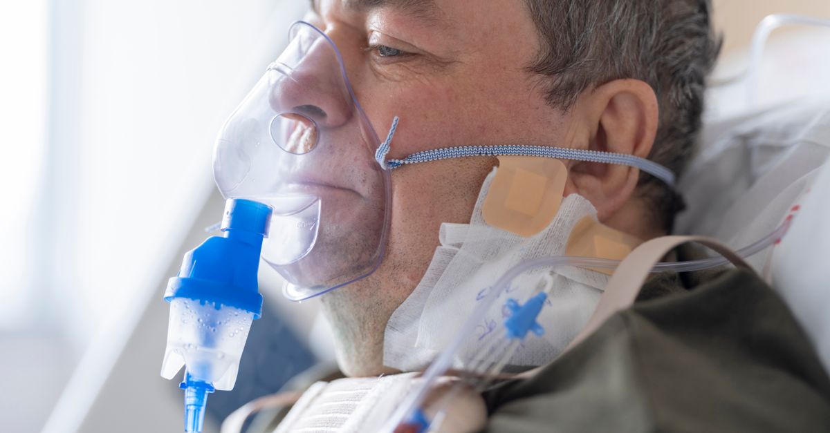 A senior adult patient using an oxygen mask in a hospital setting for medical care.