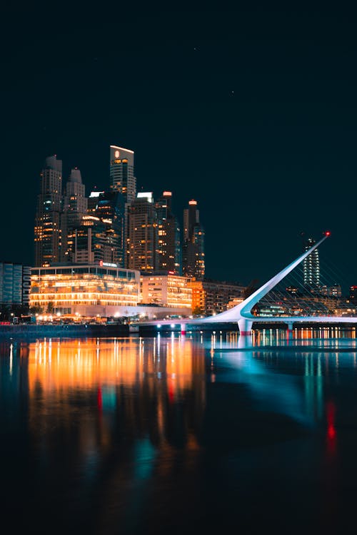 A city skyline at night with a bridge