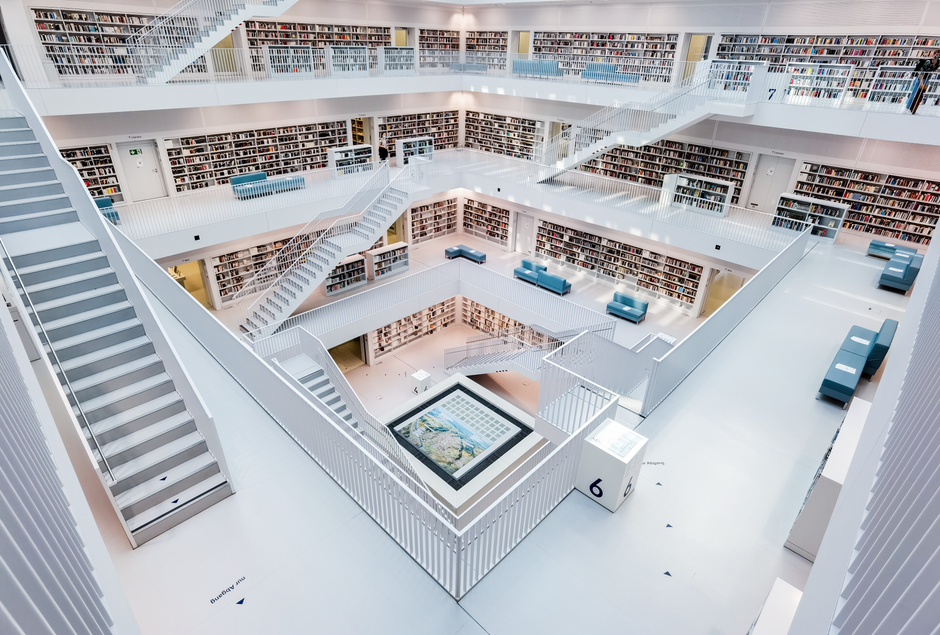 広々とした現代的な図書館で、ミニマリストの白いデザイン、豊富な本棚、座席エリアがあります。