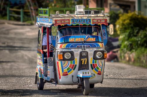 Free Vibrant rickshaw adorned with colorful decorations on a street, highlighting Colombian culture. Stock Photo