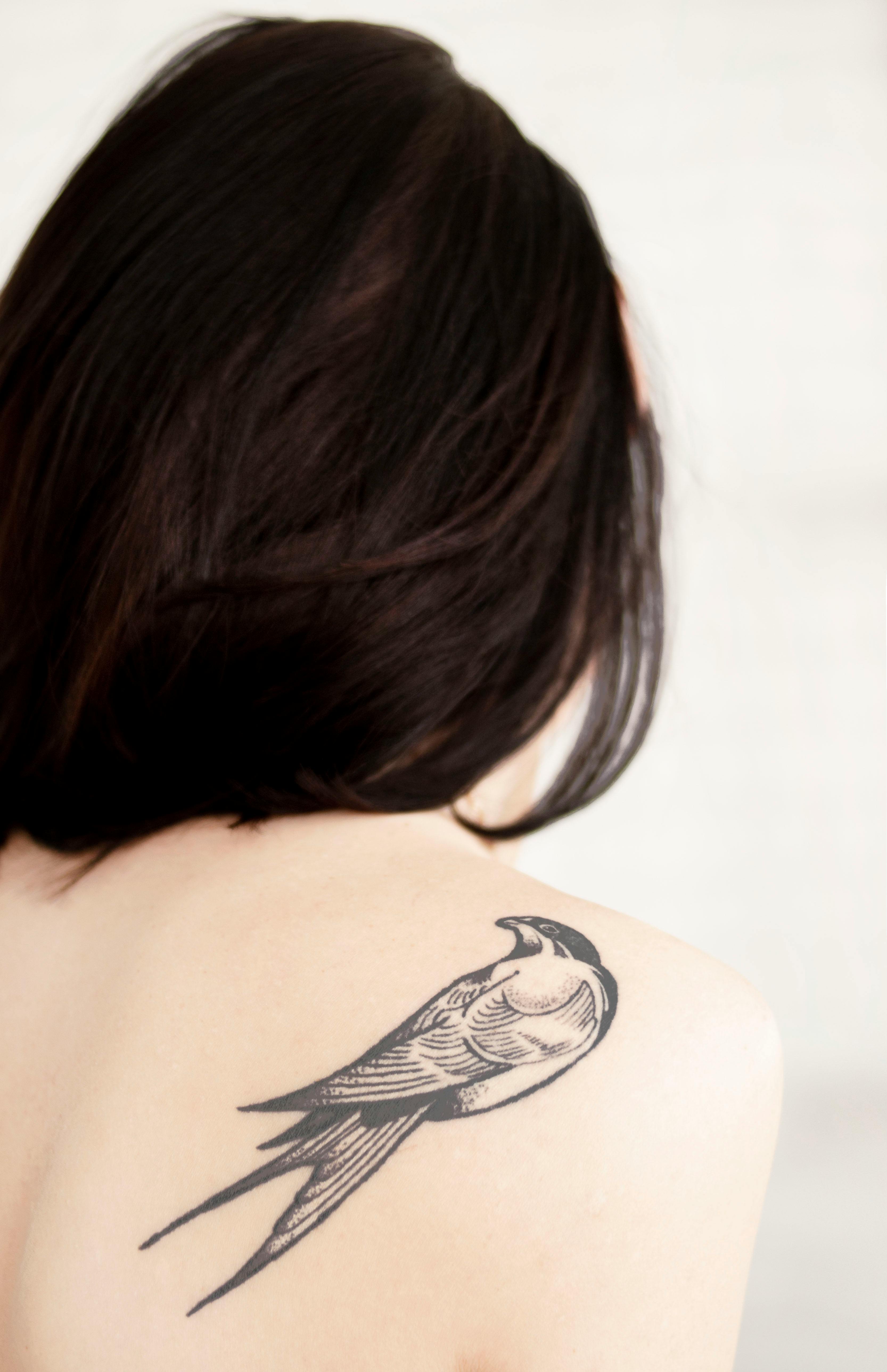 右肩に鳥のタトゥーと女性の背中のビュー 無料の写真素材