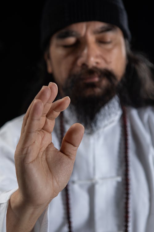 A man with long hair and beard is making a gesture