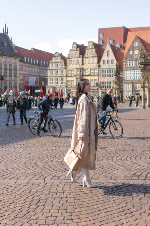 A woman in a white coat walking down a cobblestone street