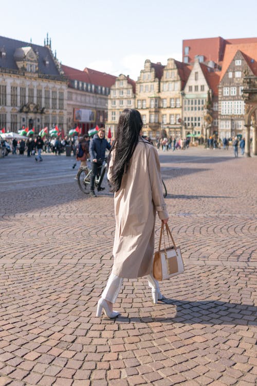 A woman walking down a cobblestone street in front of a building