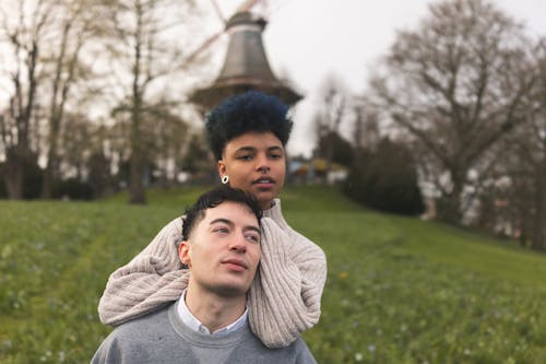 A man and woman are standing in front of a windmill