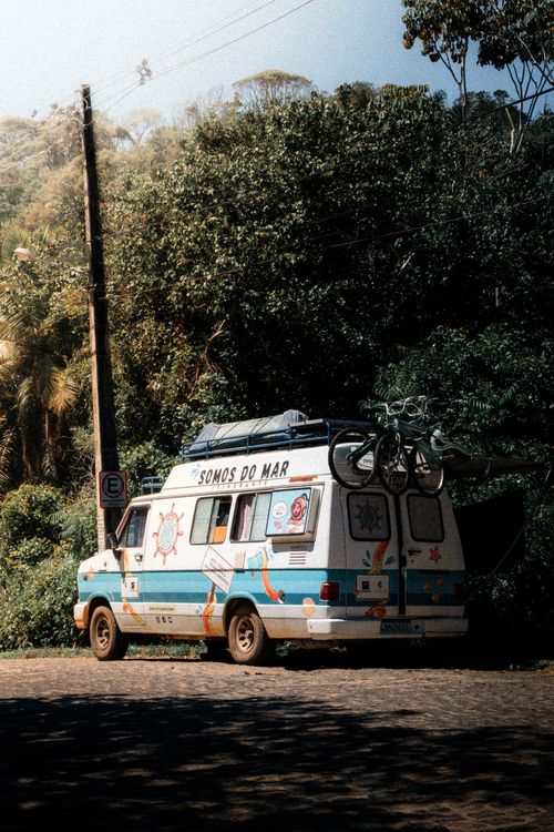 Free View of a colorful camper van parked among lush greenery on a sunny day in Brazil. Stock Photo