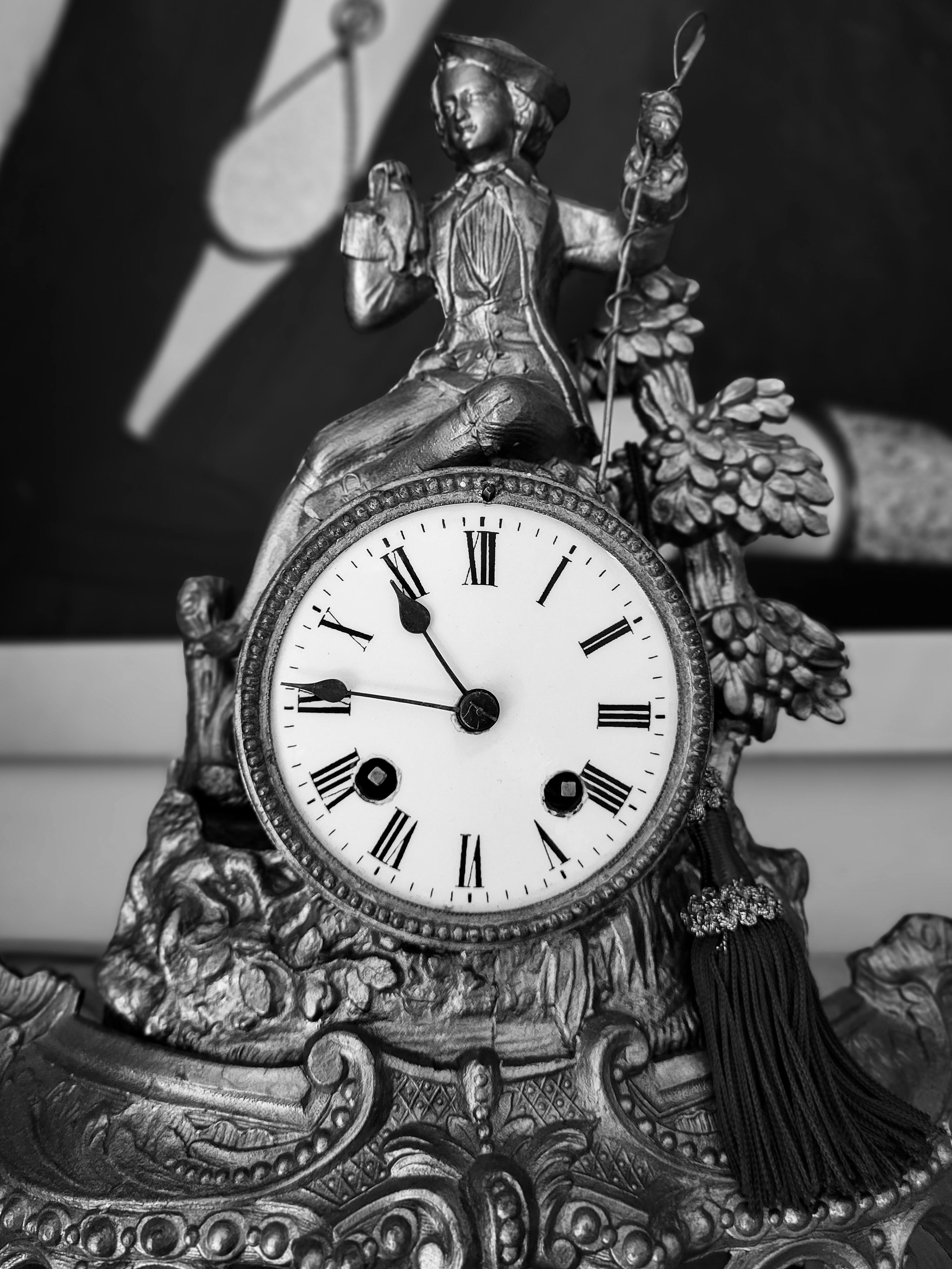 Vintage clock sculpture with intricate metalwork captured in black and white.