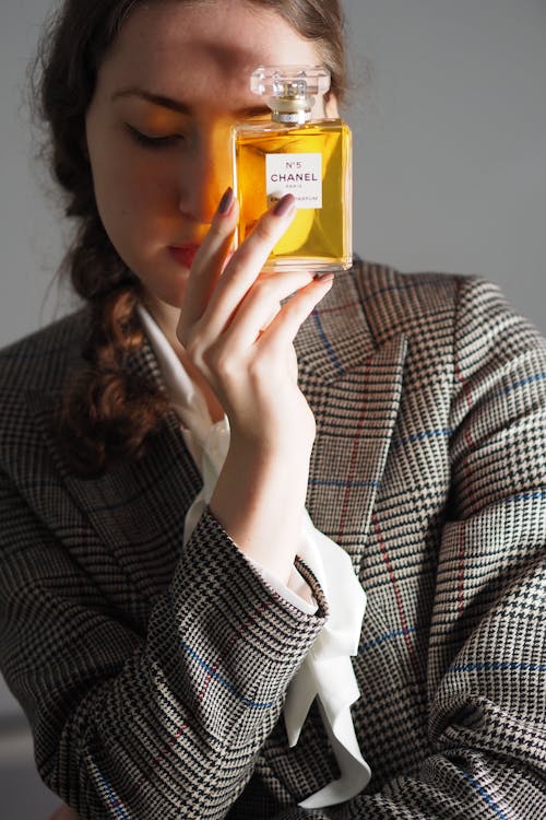 A woman holding a perfume bottle in front of her face
