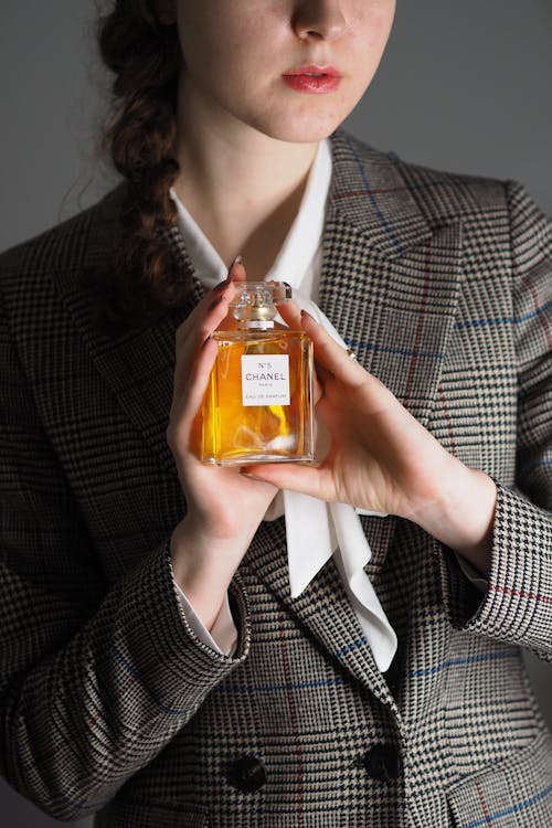 A woman in a suit holding a bottle of perfume