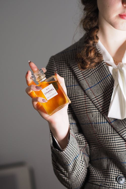A woman in a suit holding a bottle of perfume