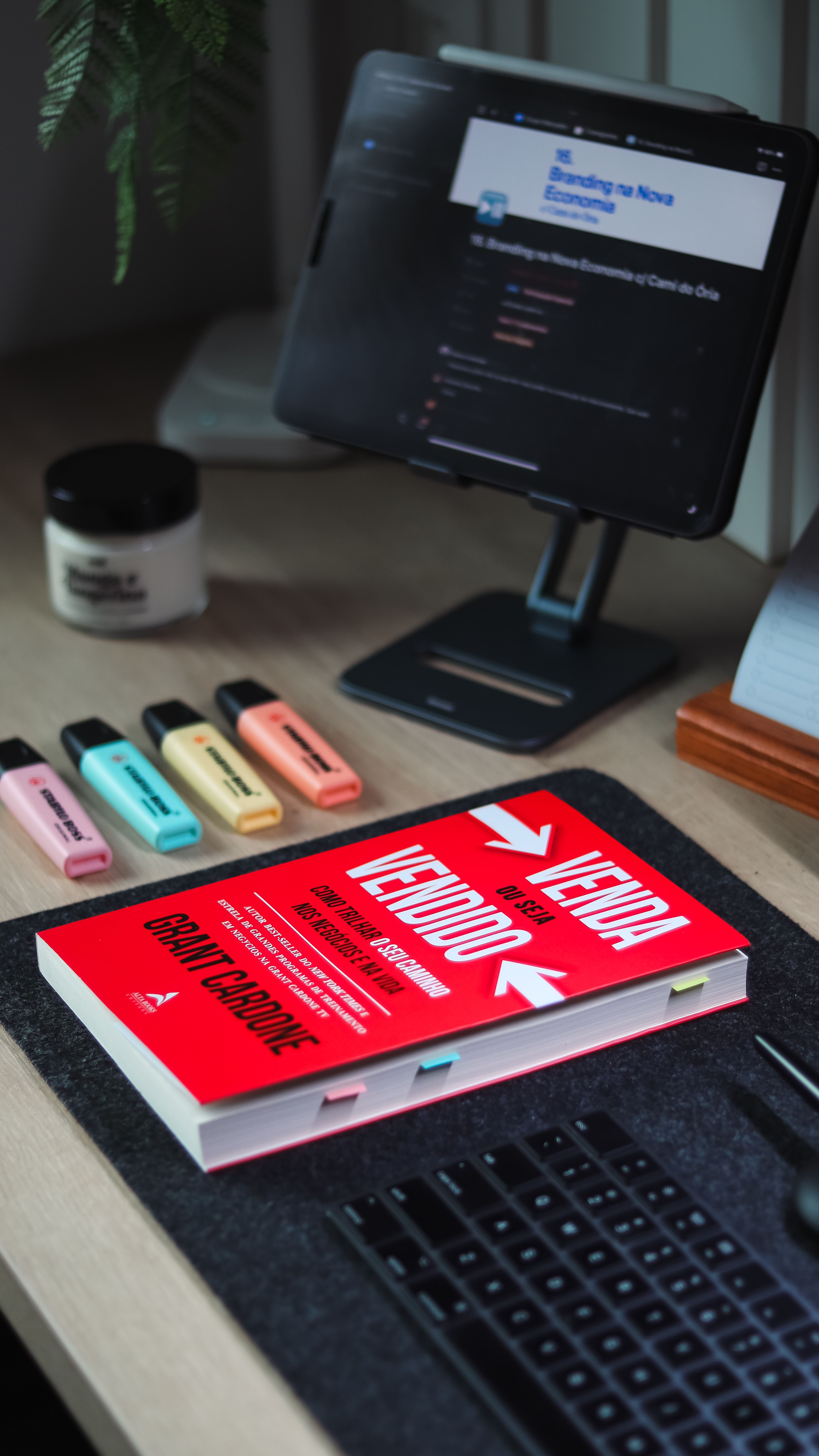 Mesa organizada com livro, tablet e teclado, representando estudo e organização financeira