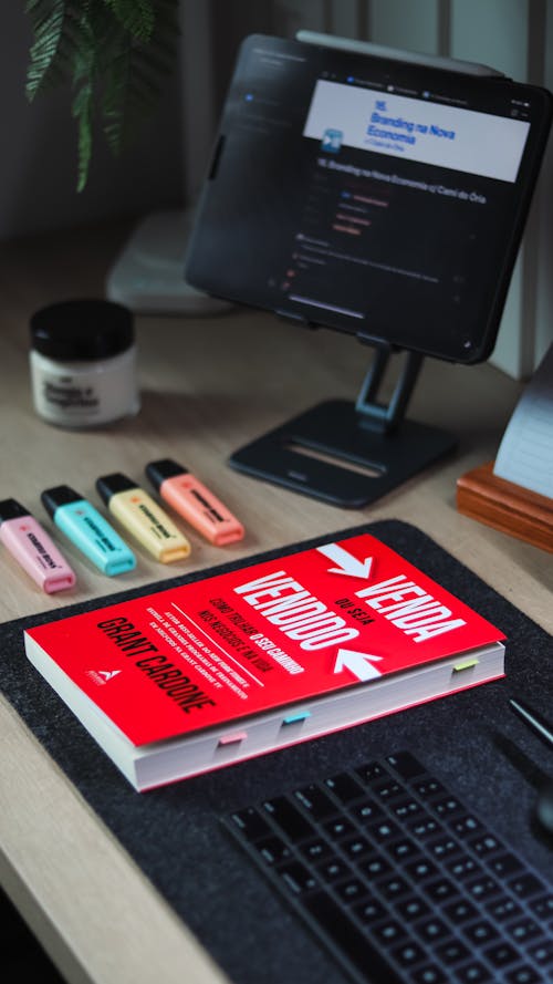 A book on a desk with a computer and keyboard