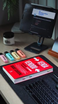 Mesa de estudos com livro sobre educação financeira, tablet e marca-textos coloridos