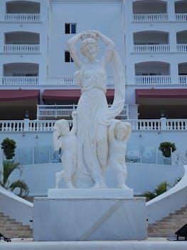 Grand marble statue of woman and children at a luxury hotel entrance, showcasing elegance.