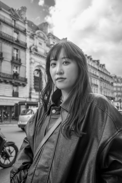 A woman in a leather jacket standing in front of a city street