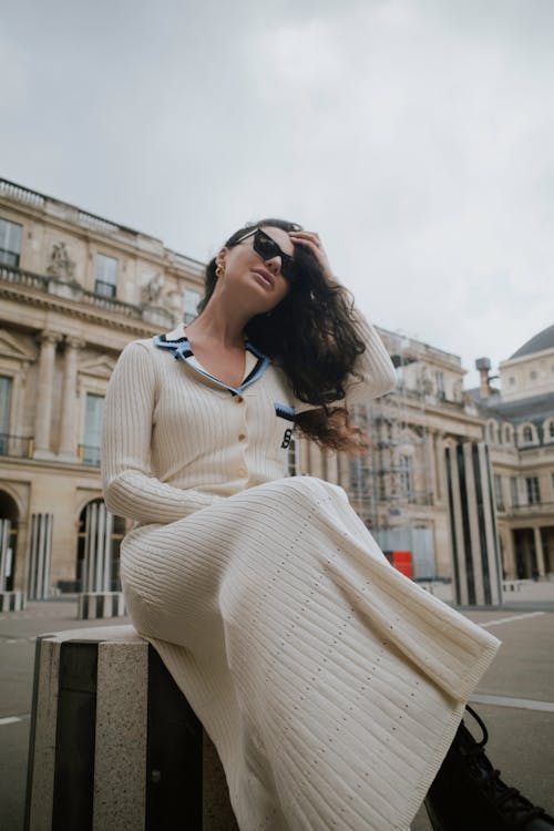 A woman in a white sweater and sunglasses sitting on a bench