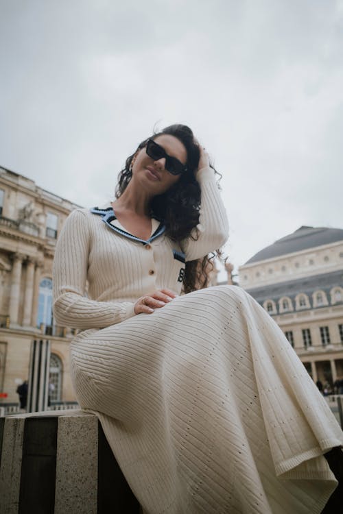 A woman in a white sweater dress and sunglasses