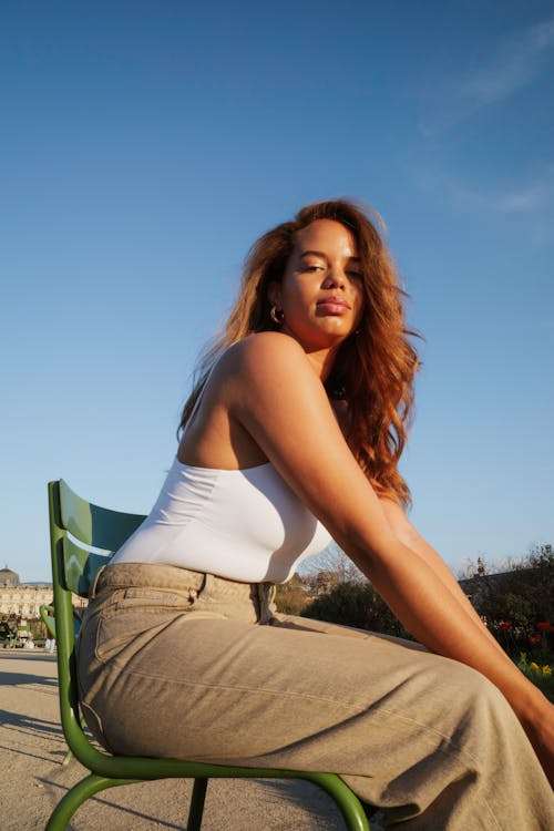 A woman sitting on a park bench with her legs crossed