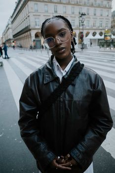Stylish woman in leather jacket at city crosswalk.