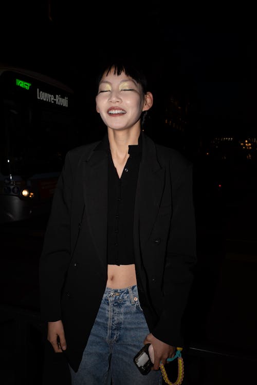 A woman in a black jacket and jeans smiling