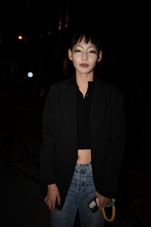 A woman in a black jacket and jeans at night