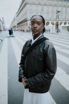 Portrait of a young woman in a leather jacket on city street crossing.