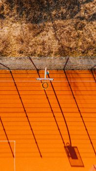Drone shot of an orange basketball court with dramatic shadows in Berlin.