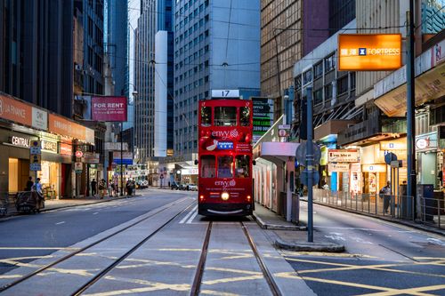 Free Vibrant Hong Kong street with a classic red tram surrounded by tall buildings and city life. Stock Photo