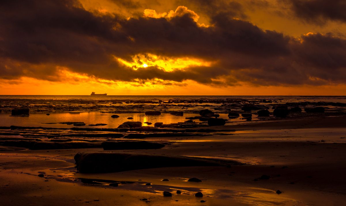 Atardecer sobre el mar bajo un cielo anaranjado