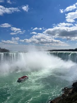 Capture the breathtaking scenery of Niagara Falls with a passenger boat navigating the misty waters.