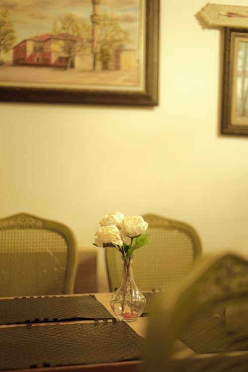 A table with a vase of flowers and a painting on the wall