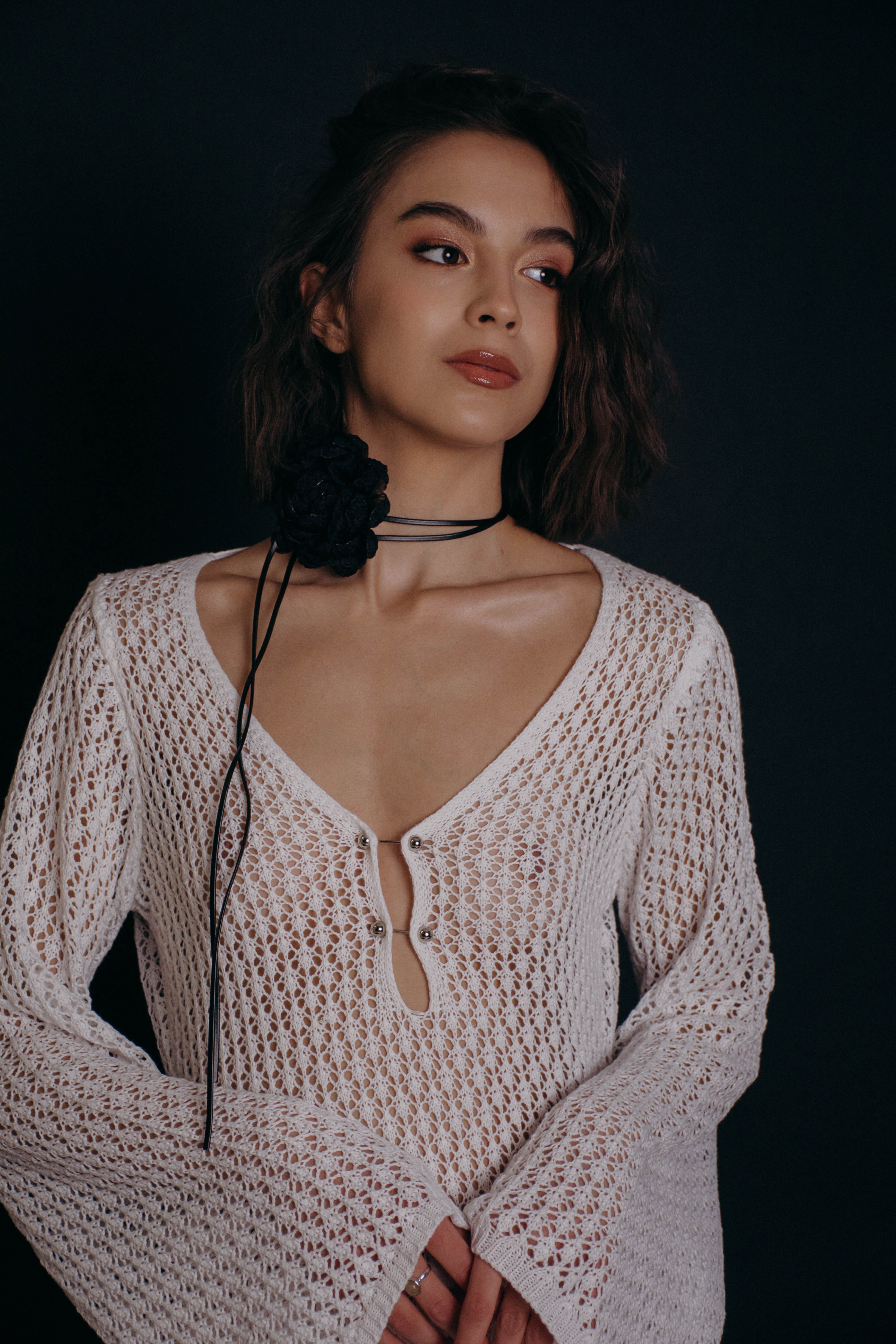 Elegant portrait of a woman wearing a white crochet top, captured in a studio setting.